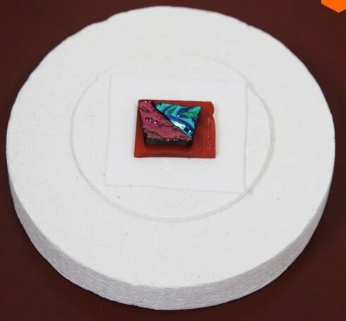 Colorful square tile on a white disc.
